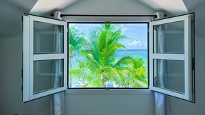 A room with a skylight and a view of palm trees and the ocean. - Beachfront villa private pool & stunning views (Saint-François)
