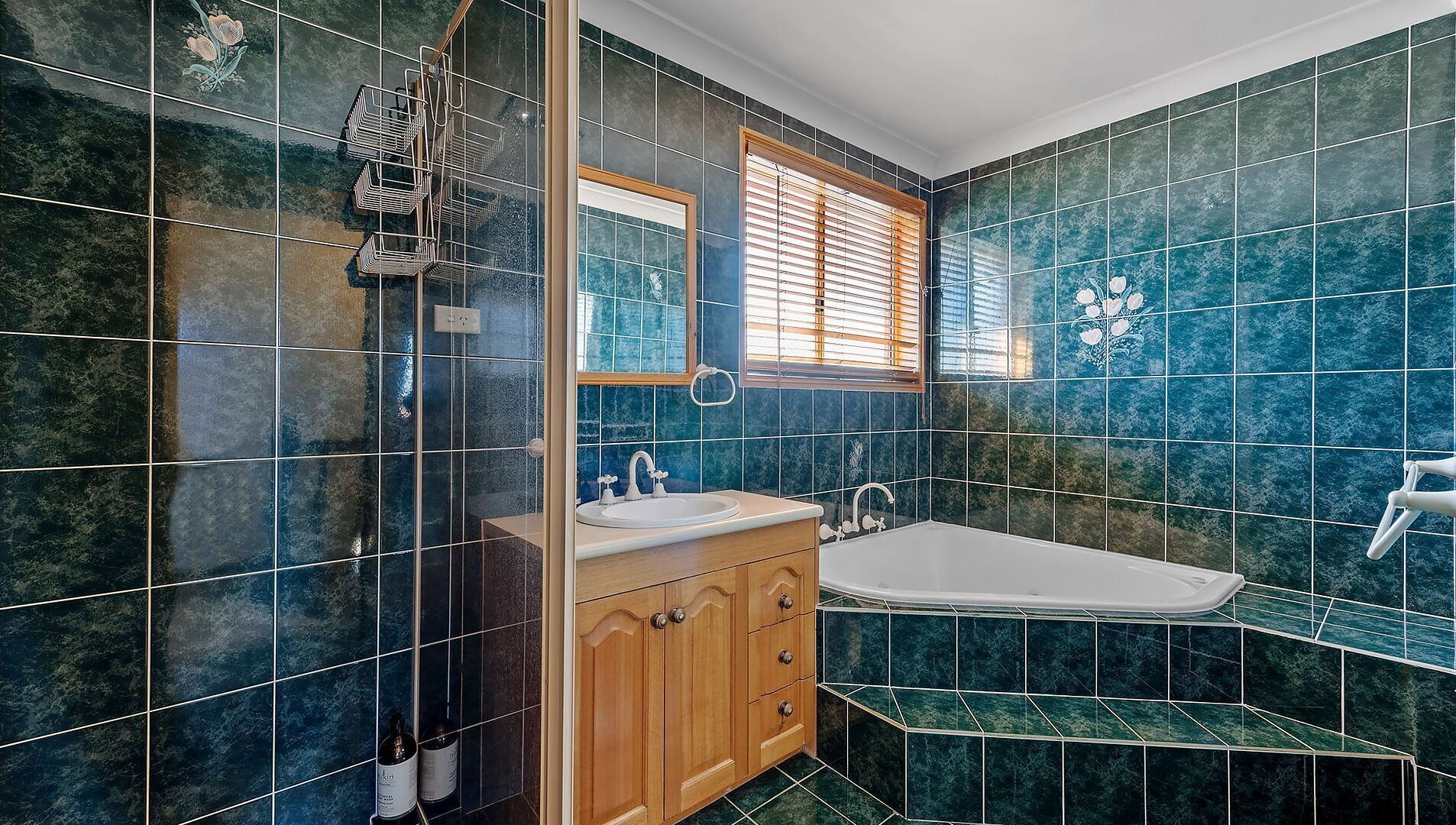 Une salle de bain avec des carreaux bleu foncé, un meuble-lavabo en bois et une baignoire.