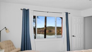 Ein Schlafzimmer mit großem Fenster, einem Sessel, einem Bett und einer Tür.