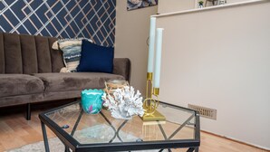 A living room with a glass coffee table, a brown sofa, and decorative items.