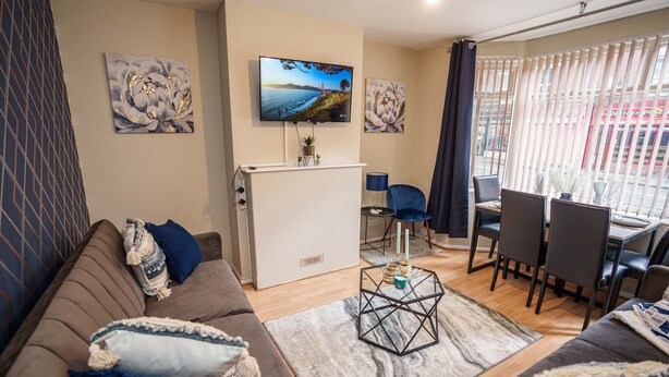 A living room with a sofa, coffee table, TV, and dining area.
