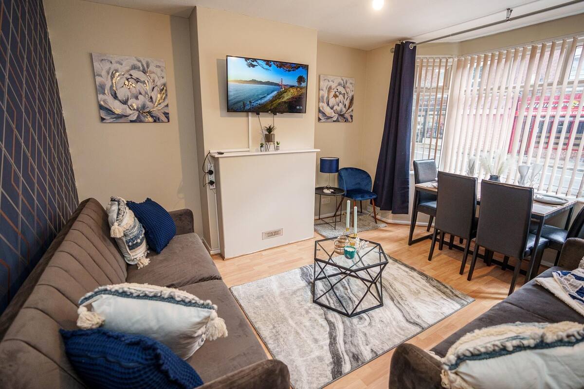 A living room with a sofa, coffee table, TV, and dining area.