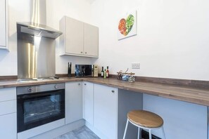 Eine moderne Küche mit weißen Schränken, einer Edelstahl-Dunstabzugshaube und einer Holz Arbeitsplatte.