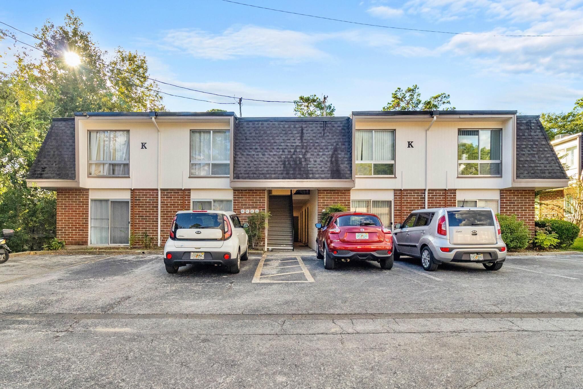 A two-story building with a parking lot. There are three cars parked in front.