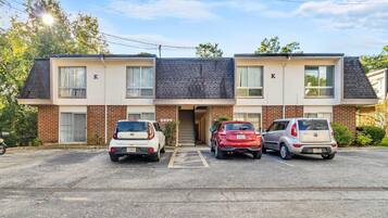 A two-story building with a parking lot. There are three cars parked in front.