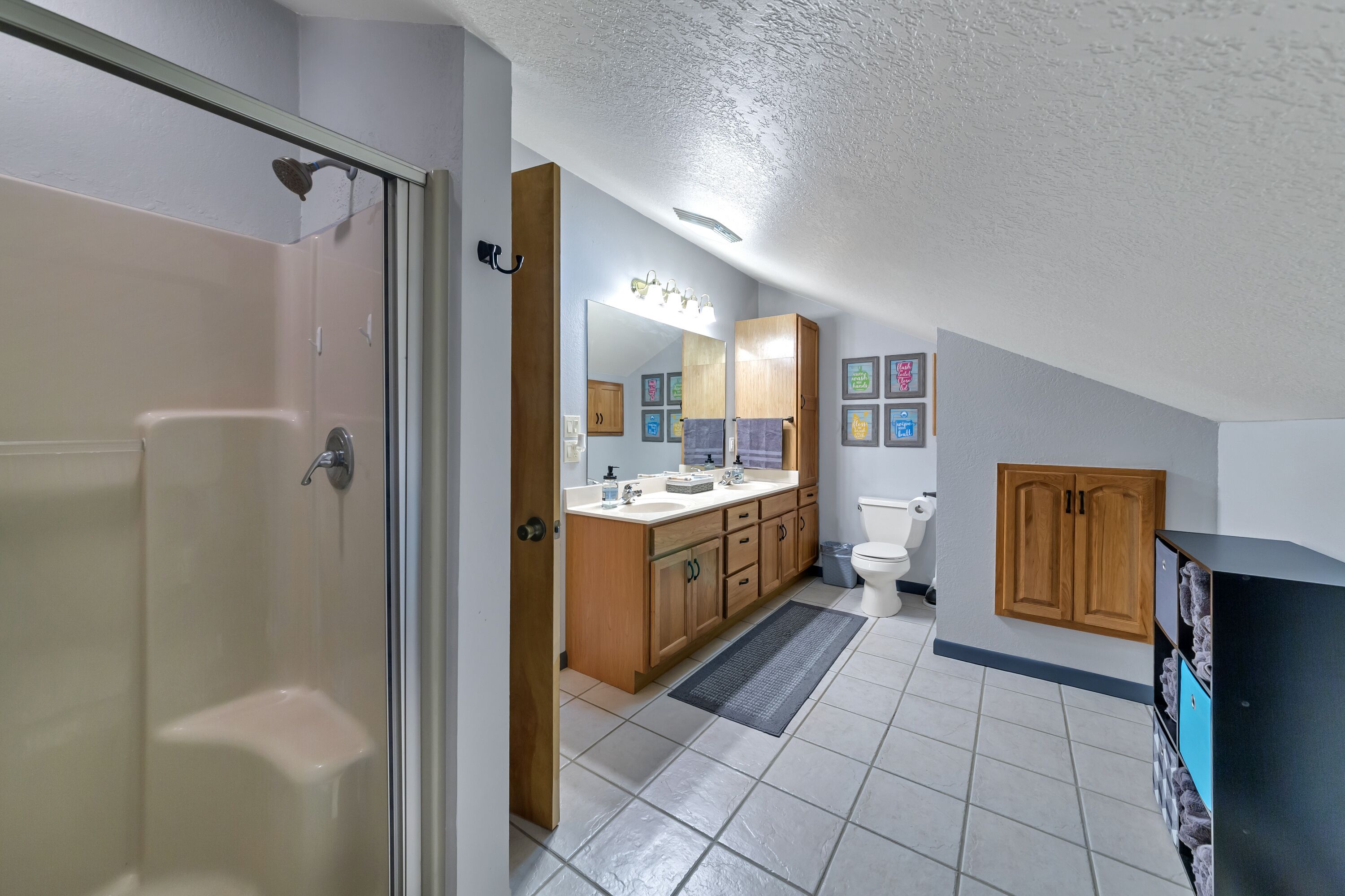 Ein Badezimmer mit Dusche, Toilette, Waschtisch und Schränken.