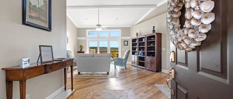 Un salón amplio con suelo de madera, un ventanal grande, un sofá y un adorno decorativo de conchas marinas.