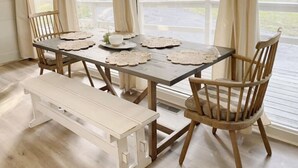 Un coin repas avec une table en bois, quatre chaises et un banc.
