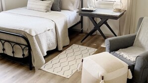 Une chambre à coucher avec un lit, une table de chevet, une lampe, une chaise et un tableau au mur.