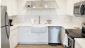 Une cuisine moderne avec des meubles blancs, un réfrigérateur en acier inoxydable, un lave-vaisselle et un four à micro-ondes.