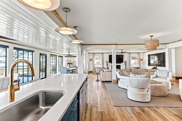 Una cocina moderna con una isla grande, un comedor con vistas y una sala de estar con sofá y sillones.