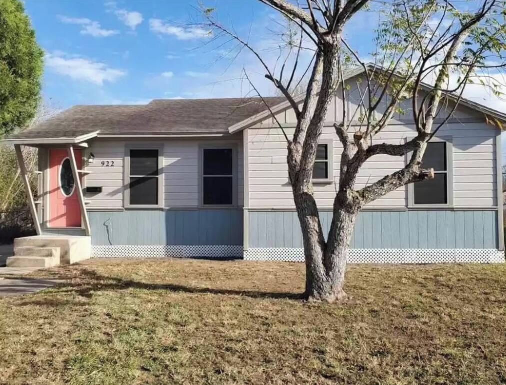 Une maison de plain-pied avec une porte d’entrée, un petit porche et un arbre devant.
