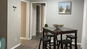 A dining area with a table and four stools, a ceiling light, and a framed picture on the wall. - Quiet and Cozy Cottage -10 minutes from the beach! (Corpus Christi)