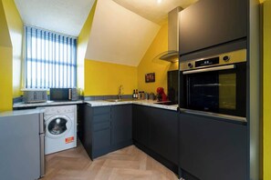Eine kompakte Küche mit Waschmaschine, Backofen und Mikrowelle.