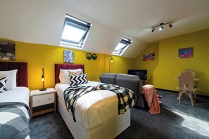 A bedroom with a bed, two bedside tables, a desk, a chair, and a skylight.