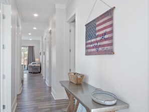 A hallway with a wooden floor, a bench with a basket, and a wall-mounted American flag with a signature. - Mallard Pointe 100 - Luxury condo- conveniently located! (Cullman)