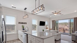 A modern kitchen with a large island, white cabinetry, and a ceiling fan. - Mallard Pointe 100 - Luxury condo- conveniently located! (Cullman)