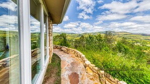 A stone pathway leading to a glass door, overlooking a lush green landscape with hills and a clear sky. - Tiger by the Tail Pets OK | Casita & Courtyard Oasis  w/ Heated Pool (Ruidoso Downs)