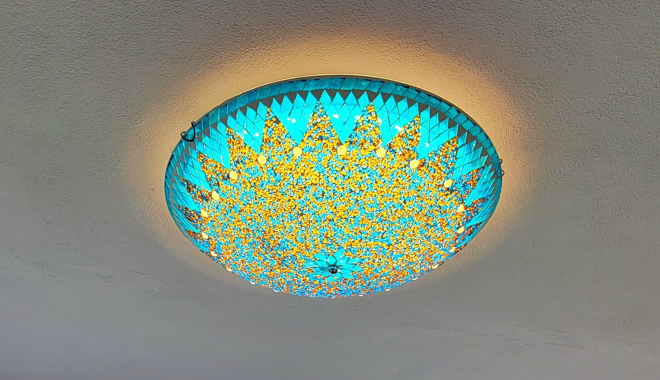 A circular ceiling light fixture with a mosaic pattern.