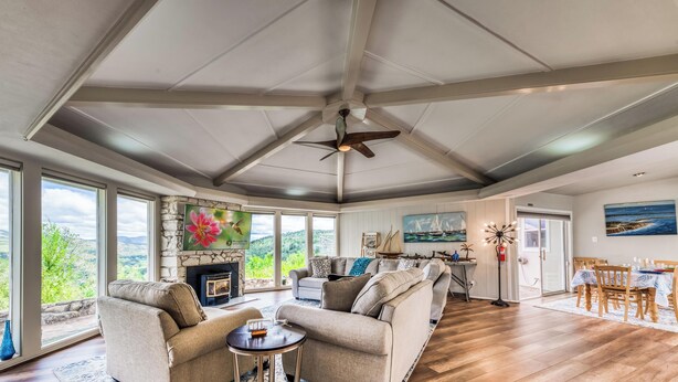 A spacious living room with a fireplace, large windows, and a dining area. - Tiger by the Tail Pets OK | Casita & Courtyard Oasis  w/ Heated Pool (Ruidoso Downs)