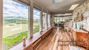 A spacious room with large windows, a stone wall, and a wooden bench. - Tiger by the Tail Pets OK | Casita & Courtyard Oasis  w/ Heated Pool (Ruidoso Downs)