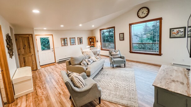 A spacious living room with a large window, a fireplace, and a dining area. - Cozy up in this private bungalow in the trees close to trailheads & shopping (Kodiak)