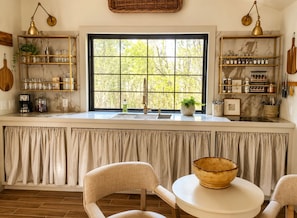 Una cocina con un ventanal amplio, un lavabo y una encimera con distintos objetos.