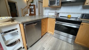 A modern kitchen with stainless steel appliances, wooden cabinets, and a granite countertop. - 5 Min. Drive to the Resort and Fernie (Fernie)