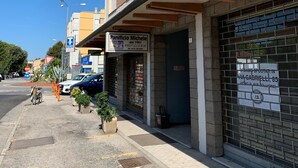Vista de una calle con un edificio que muestra un letrero que dice 'Panificio Michele' y una tienda cerrada con un letrero que dice 'S. Angelo Spostattino'.
