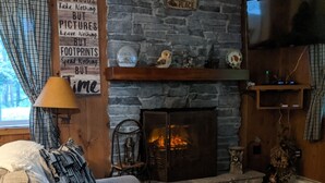 Un salón acogedor con chimenea de piedra, un sofá cómodo y un televisor montado en la pared.