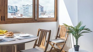 Ett modernt kök med träskåp, ett matbord och stolar. Det finns ett stort fönster med utsikt över stadsbilden.