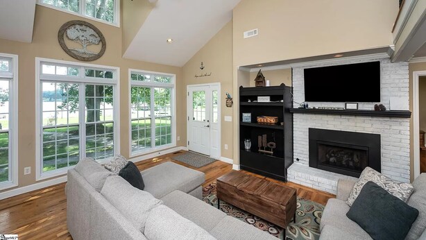 A spacious living room with a fireplace, large windows, and a ceiling fan. - Rest-Relax-Refresh (Waterloo)