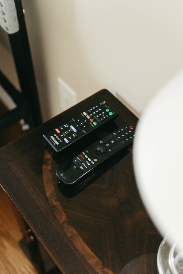 Two remote controls on a wooden table. - Rest-Relax-Refresh (Waterloo)