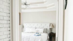 A bedroom with a white bed, a ceiling fan, and a wooden floor. - Rest-Relax-Refresh (Waterloo)