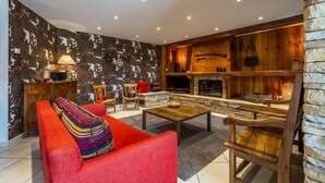 A cozy living room with a fireplace, wooden walls, and a red sofa. - Martirenia - Osses - Gîte (OSSES)