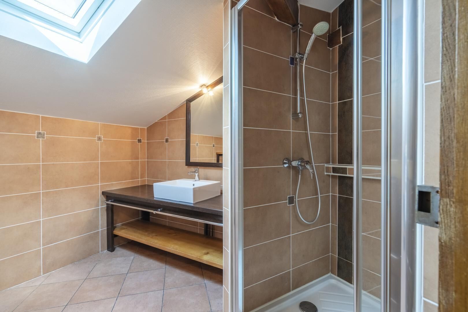 A modern bathroom with a skylight, a shower, and a vanity with a mirror.