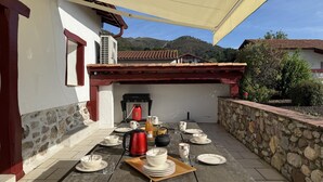 An outdoor patio with a table set for dining, a red kettle, and a portable stove. - Martirenia - Osses - Gîte (OSSES)