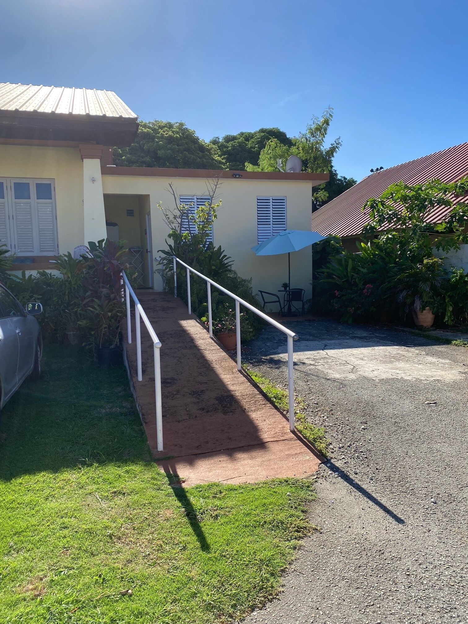 A building with a paved entrance, a gravel driveway, and a car parked to the left.
