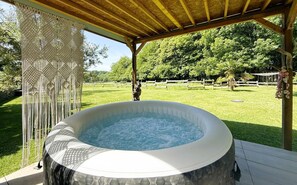 A hot tub under a wooden pergola with a grassy yard and trees in the background. - Gite DU Chene - Ledeuix (LEDEUIX)