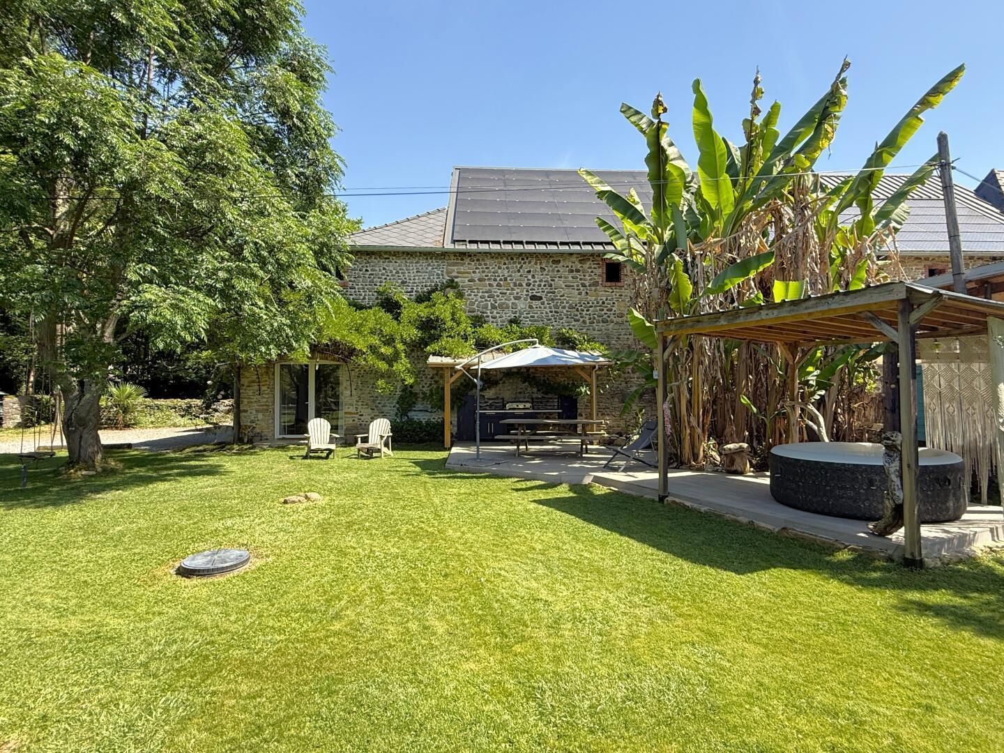 A stone building with a covered patio, outdoor seating, and a well-maintained lawn.