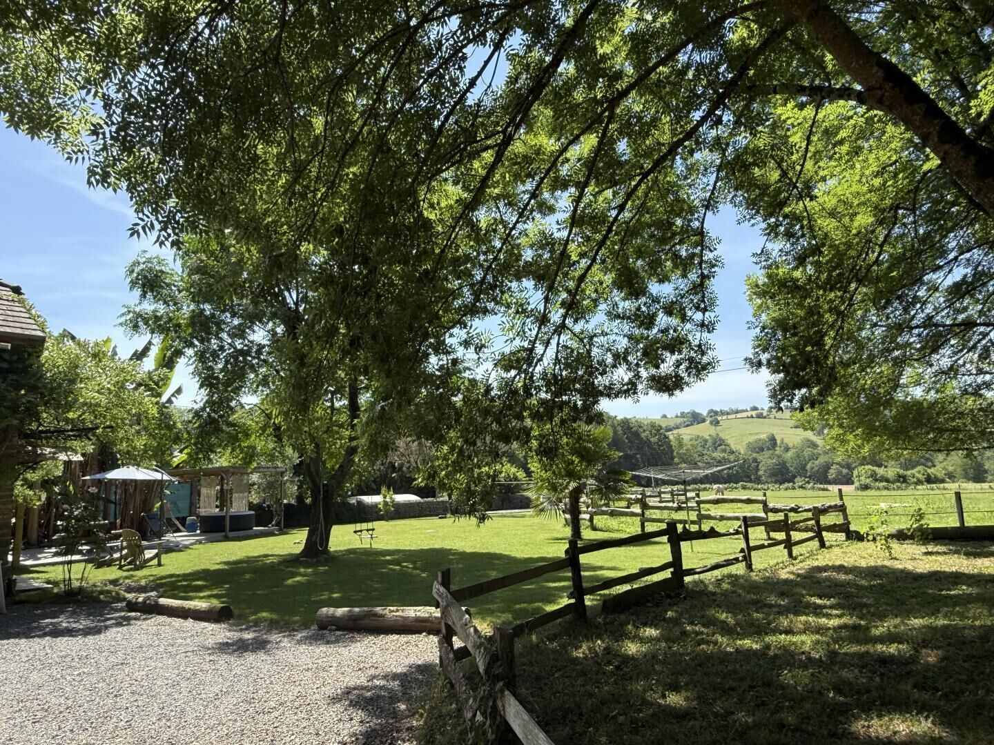 A rural setting with a wooden fence, a grassy area, and a building in the background.