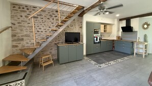 A modern kitchen with grey cabinets, a built-in oven, and a ceiling fan. - Gite DU Chene - Ledeuix (LEDEUIX)