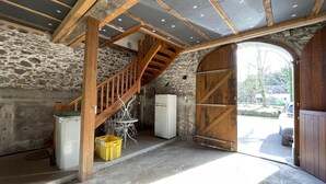 A rustic interior with a stone wall, wooden staircase, and a large wooden door leading outside. - Chez Algorry - Aramits (ARAMITS)