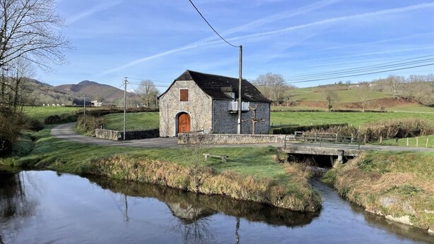 A stone building with a wooden door, a small bridge over a calm river, and a rural landscape with hills in the background. - Chez Algorry - Aramits (ARAMITS)