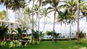 A resort with a grassy lawn, palm trees, and outdoor seating. - Charmant T1 avec vue sur la marina (Les Trois-Îlets)