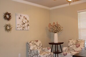 Relax in a serene space with two armchairs, a side table, and beautiful botanical art.