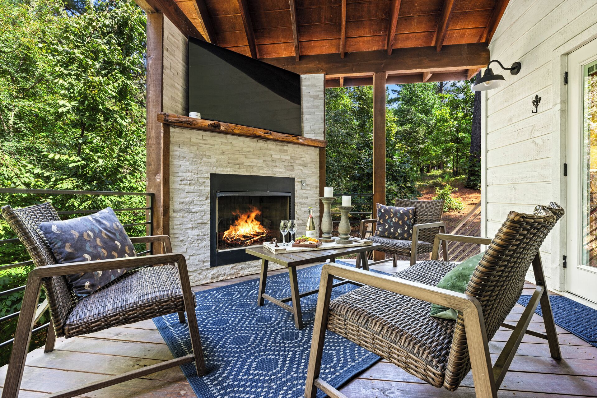 An outdoor patio with a brick fireplace, wicker furniture, and a wooden deck.