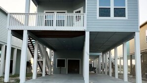 A two-story building with a covered front porch and a balcony. - Gorgeous Beach House w/Pop Up Bar & Community Pool (Rockport)