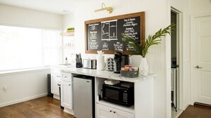 A kitchen with white cabinetry, a chalkboard menu, a microwave, and a refrigerator. - The 1842 Suite - Millpond Inn (Clarkston)