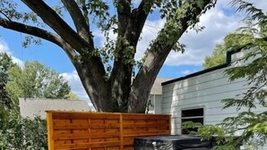 A backyard with a stone pathway, a wooden fence, and a hot tub. - The 1842 Suite - Millpond Inn (Clarkston)